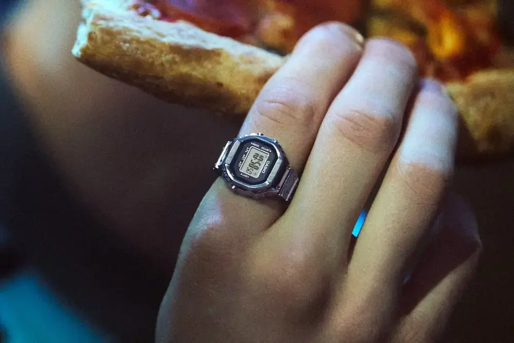 A hand with a ring that looks like a casio watch on one finger.