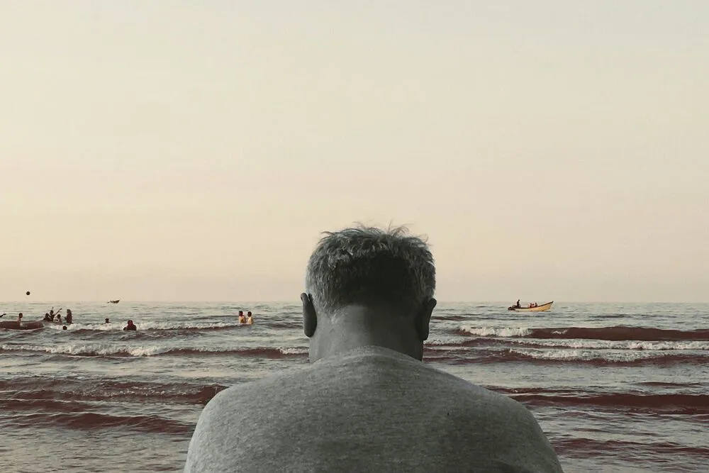 The back of the head of a man looking over the sea