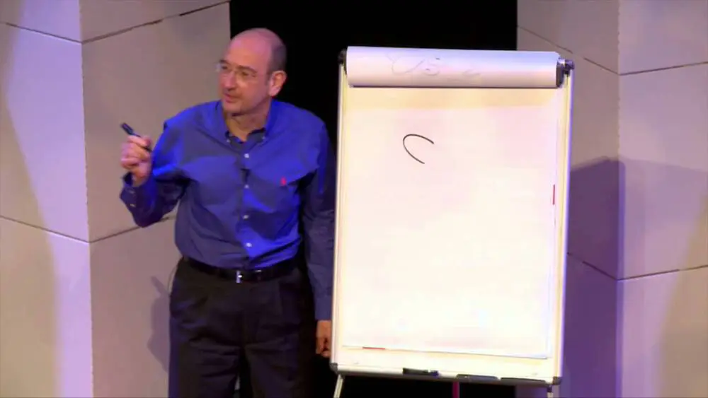 A photo of Graham at the TEDx talk, standing on the stage with a whiteboard.